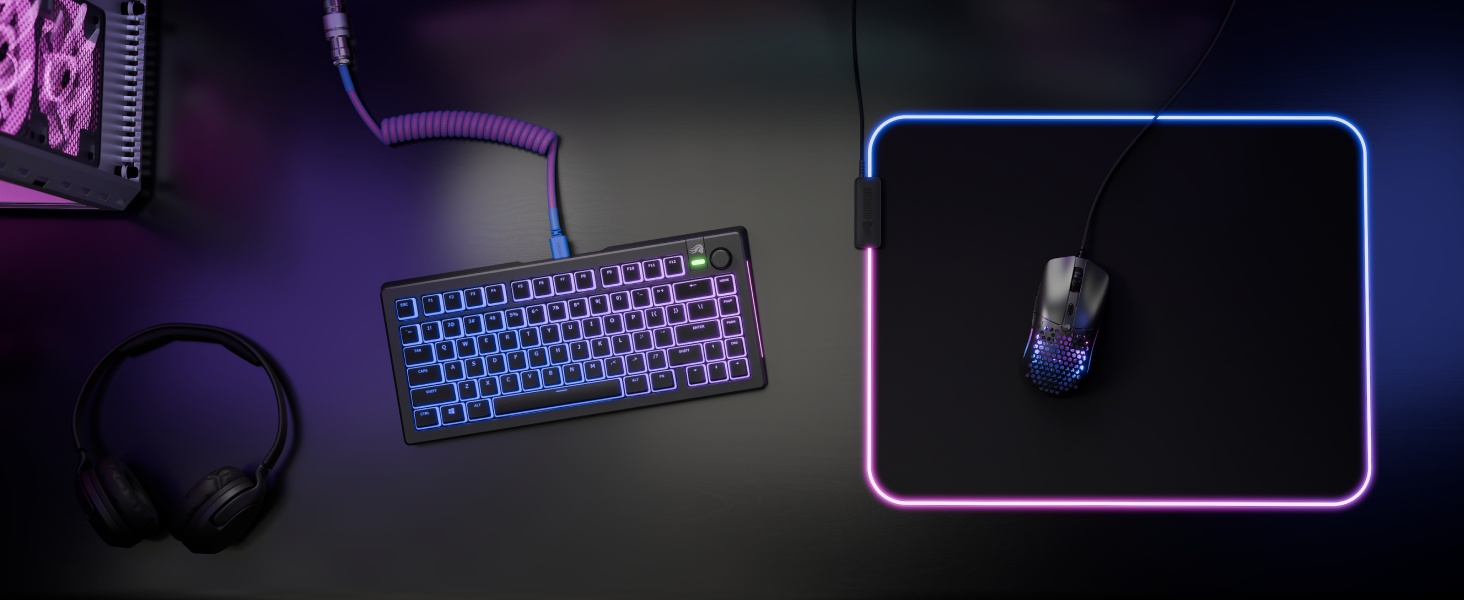 Gaming-setup met paars mechanisch toetsenbord met LED-achtergrondverlichting en muismat die oplicht in een donkere omgeving.