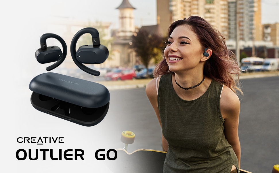 Creative Outlier Go wireless earbuds with ear hooks and charging case shown in black color against outdoor setting.
