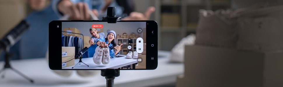 Smartphone on a tripod capturing video of a person holding a small object, demonstrating smartphone camera and video recording capabilities.