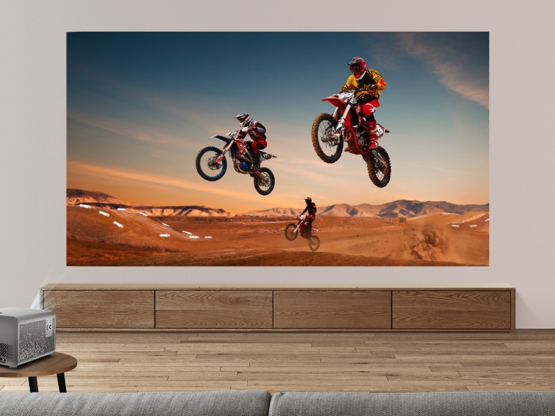 Plans d'action séquentiels de motos de cross sautant dans un paysage désertique au coucher du soleil. Des cavaliers effectuant des cascades aériennes sur un ciel orange et des dunes de sable.