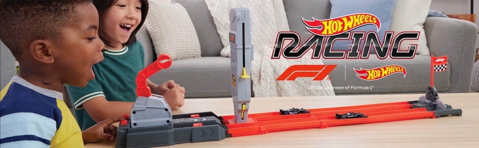 Der Text lautet „Hot Wheels“ und „Racing“. Kinder spielen auf der orangefarbenen Hot Wheels-Rennstrecke auf dem Boden, auf der die Actionsequenz eines Rennens gezeigt wird.